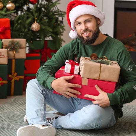 Man with santa hat holding christmas gifts smiling