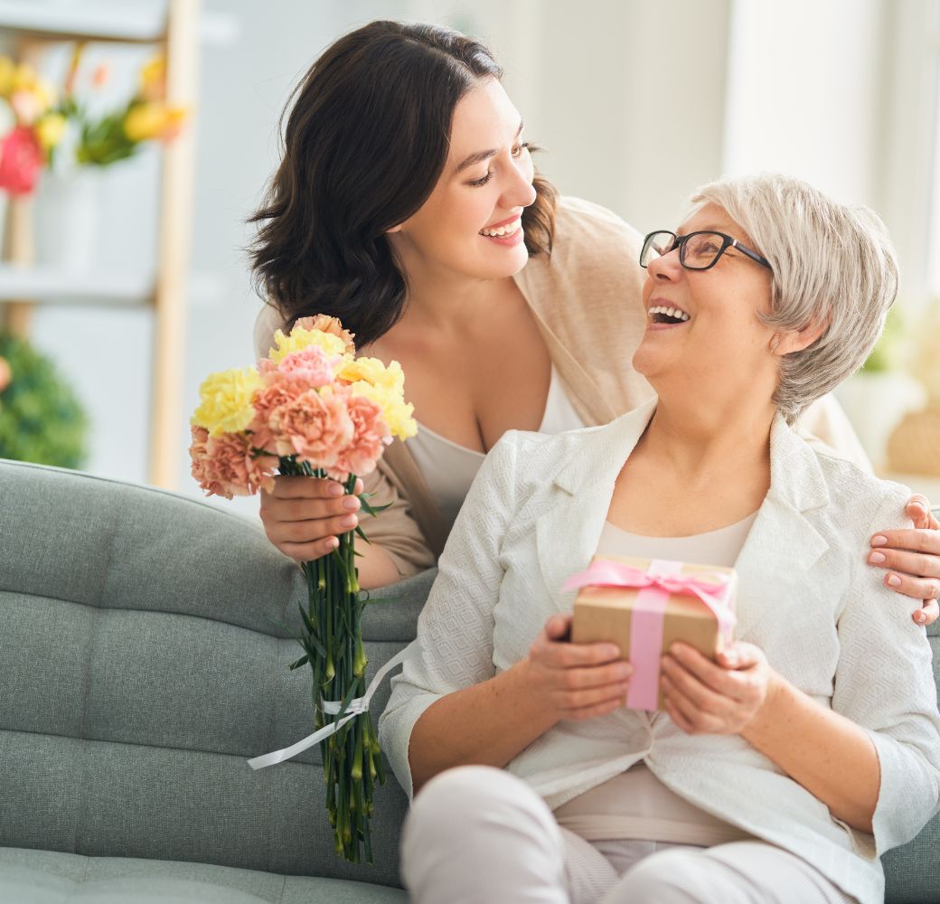 Mother and Daughter exchanging gifts and flowers and smiling at each other