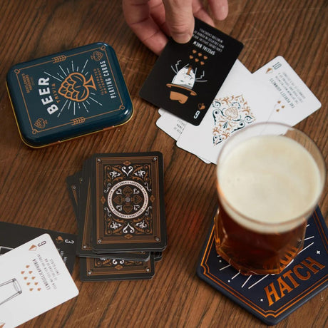 playing card on table with one card in hand and a beer on coaster