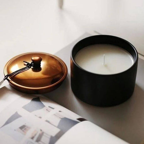 black ceramic candle with lid off on a magazine 