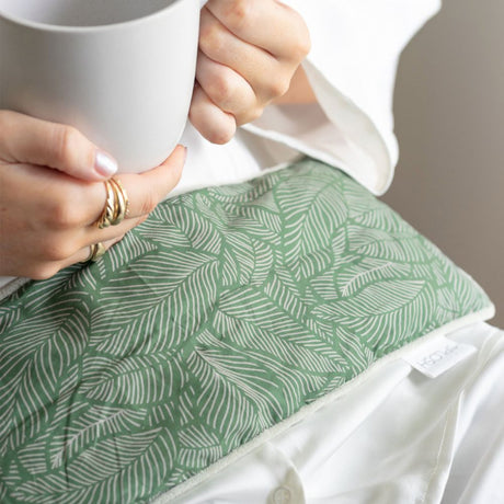 Lady holding cup with wellness heat pillow on her lap