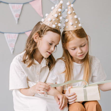 two girls opening gift with party hats on