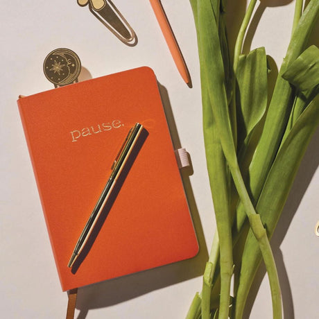 journal and pen on table with flower stems