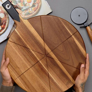hands holding gents hardware pizza cutting board with pizza cutter in the background 
